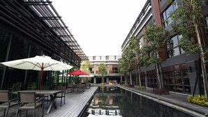 A modern outdoor pool area with wooden decking, lounge chairs, and umbrellas. - Imperial Dynasty Exquisite Hotel (Dounan)