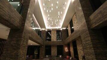 Een ruime lobby met een hoge plafond, stenen muren en een moderne kroonluchter.