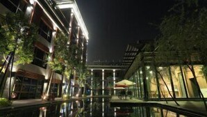 A nighttime view of a modern building with a reflective pool in the foreground. - Imperial Dynasty Exquisite Hotel (Dounan)