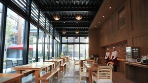 An indoor dining area with wooden tables and chairs, large windows, and a brick wall. - Imperial Dynasty Exquisite Hotel (Dounan)