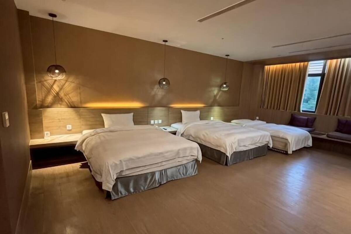 Une chambre d’hôtel avec deux lits, un bureau et une fenêtre avec des rideaux.
