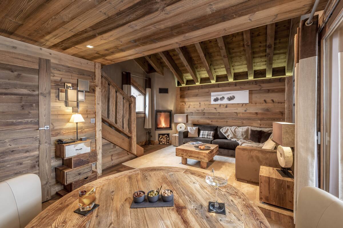 Un acogedor interior de cabaña de madera con una mesa de comedor de madera, un sofá y una chimenea.