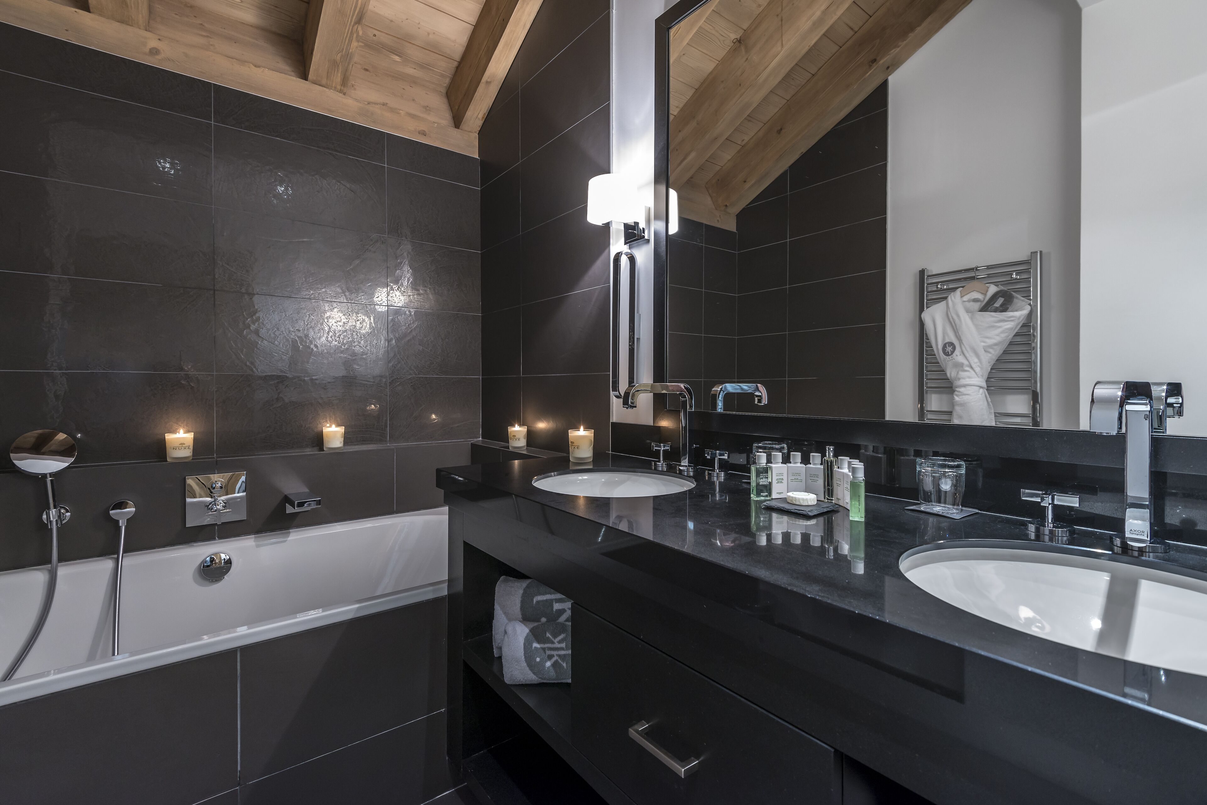 A modern bathroom with two sinks, a large mirror, and a bathtub.