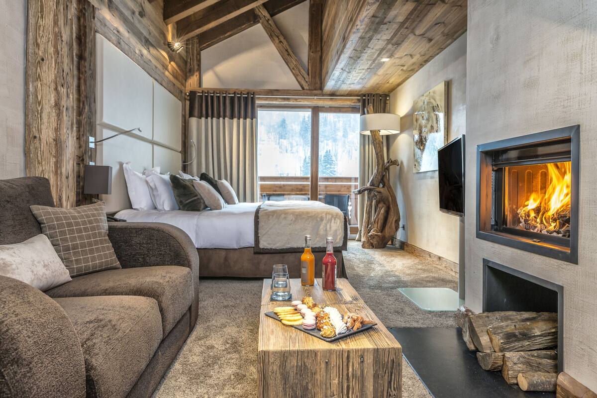 Un dormitorio acogedor con cama, una mesita de madera con aperitivos, chimenea y televisor.