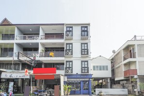 A multi-story building with balconies, a cafe named 'Cafe De Hun' on the ground floor, and a sign for 'Our Home' above a shop.