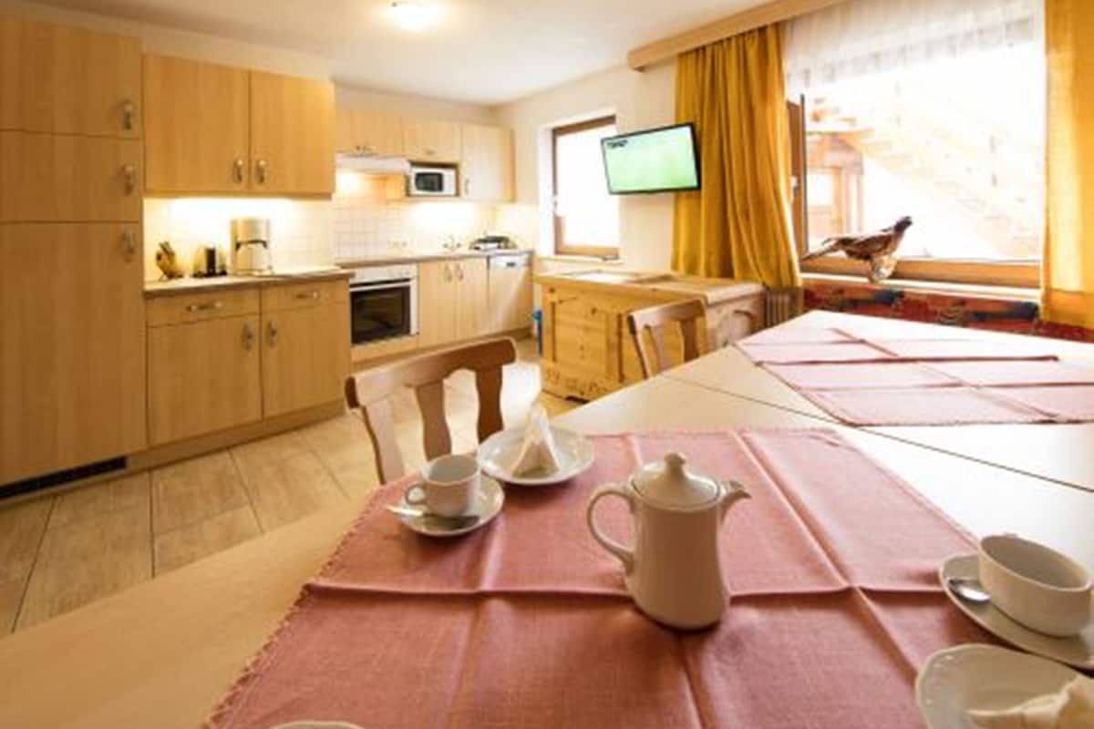 A compact kitchen with wooden cabinets, a microwave, and a dining area with a table set for two.