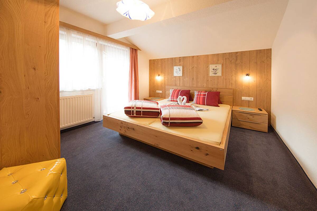 A modern bedroom with a large bed, wooden headboard, and a small bedside table.