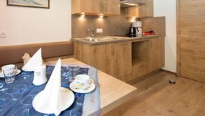 Una cocina compacta con armarios de madera, un lavamanos empotrado y una cafetera.