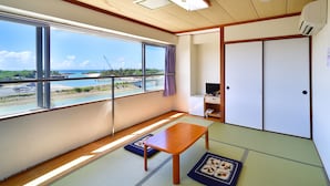 Una habitación con suelo de tatami, una mesa de madera, un televisor y una puerta corredera.