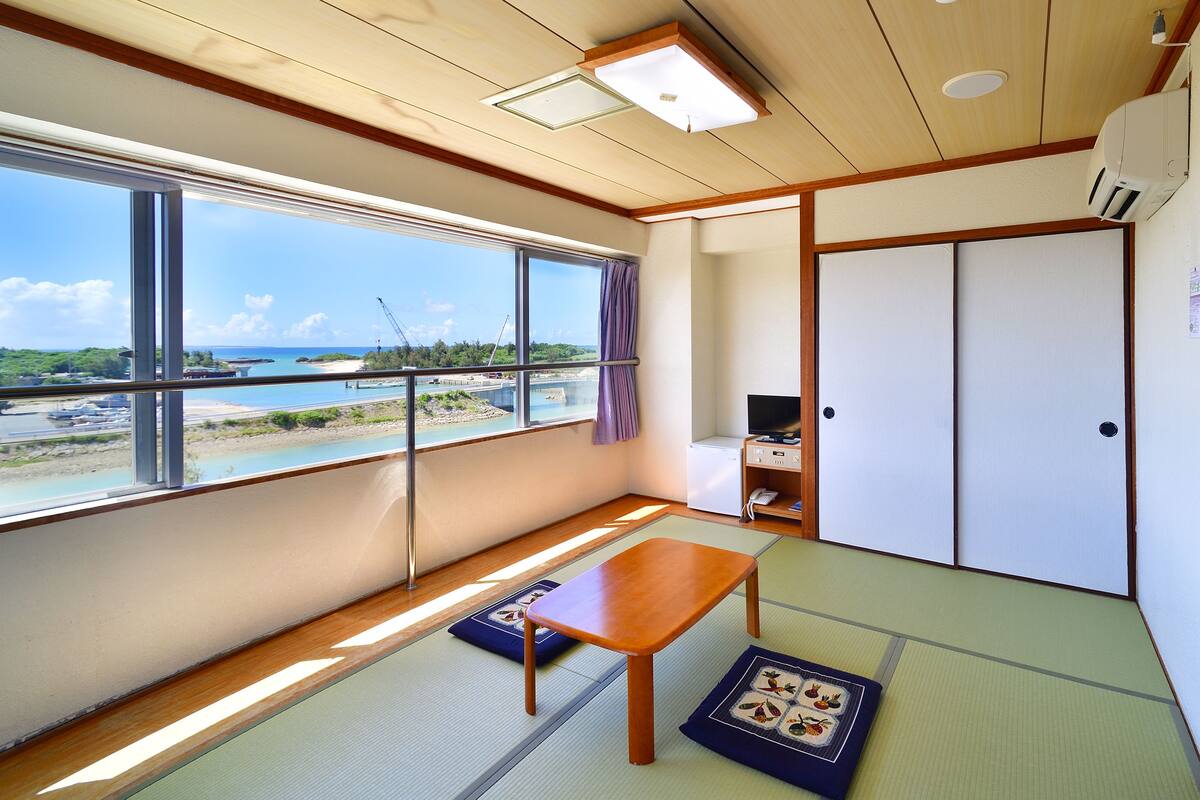 A room with tatami flooring, a wooden table, a TV, and a sliding door.