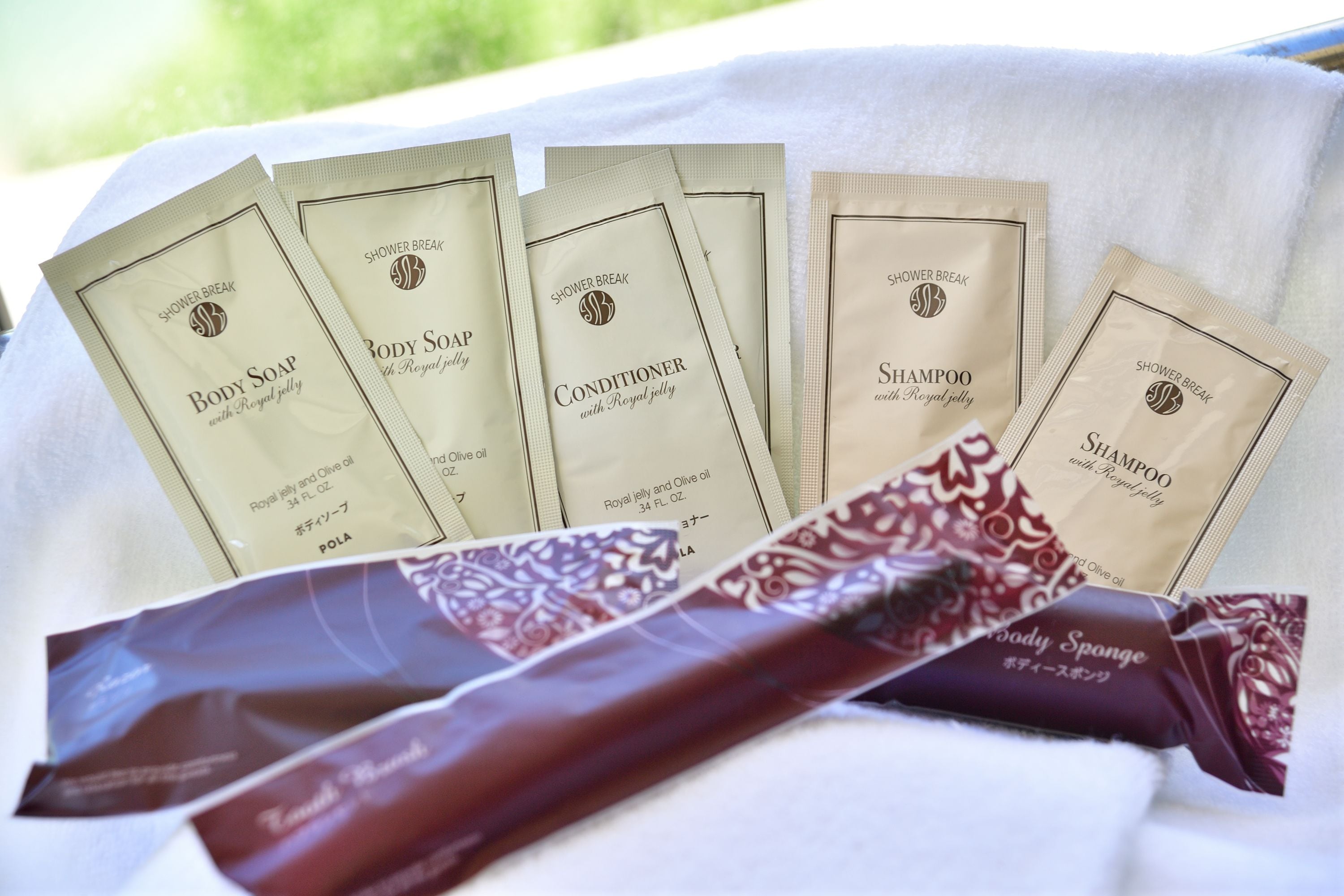 A set of toiletries including body soap, conditioner, shampoo, and body sponge, all branded with 'Royal jelly'.