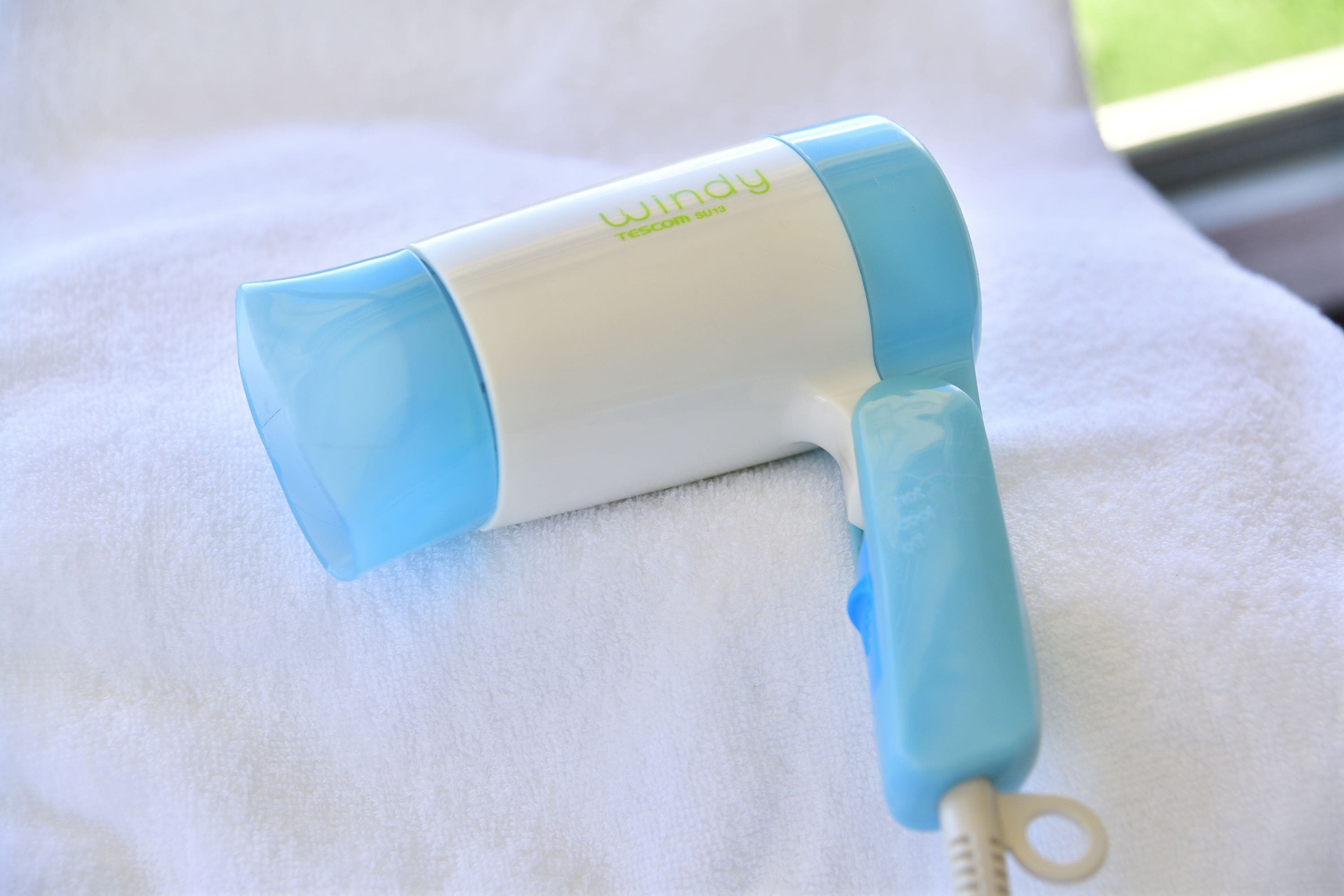 A blue and white hairdryer on a white towel.