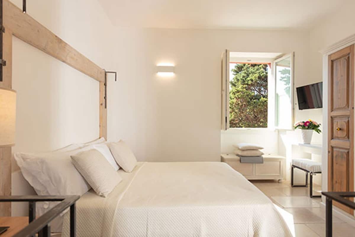 Une chambre à coucher avec un lit, une table de chevet et une fenêtre donnant sur un paysage verdoyant.