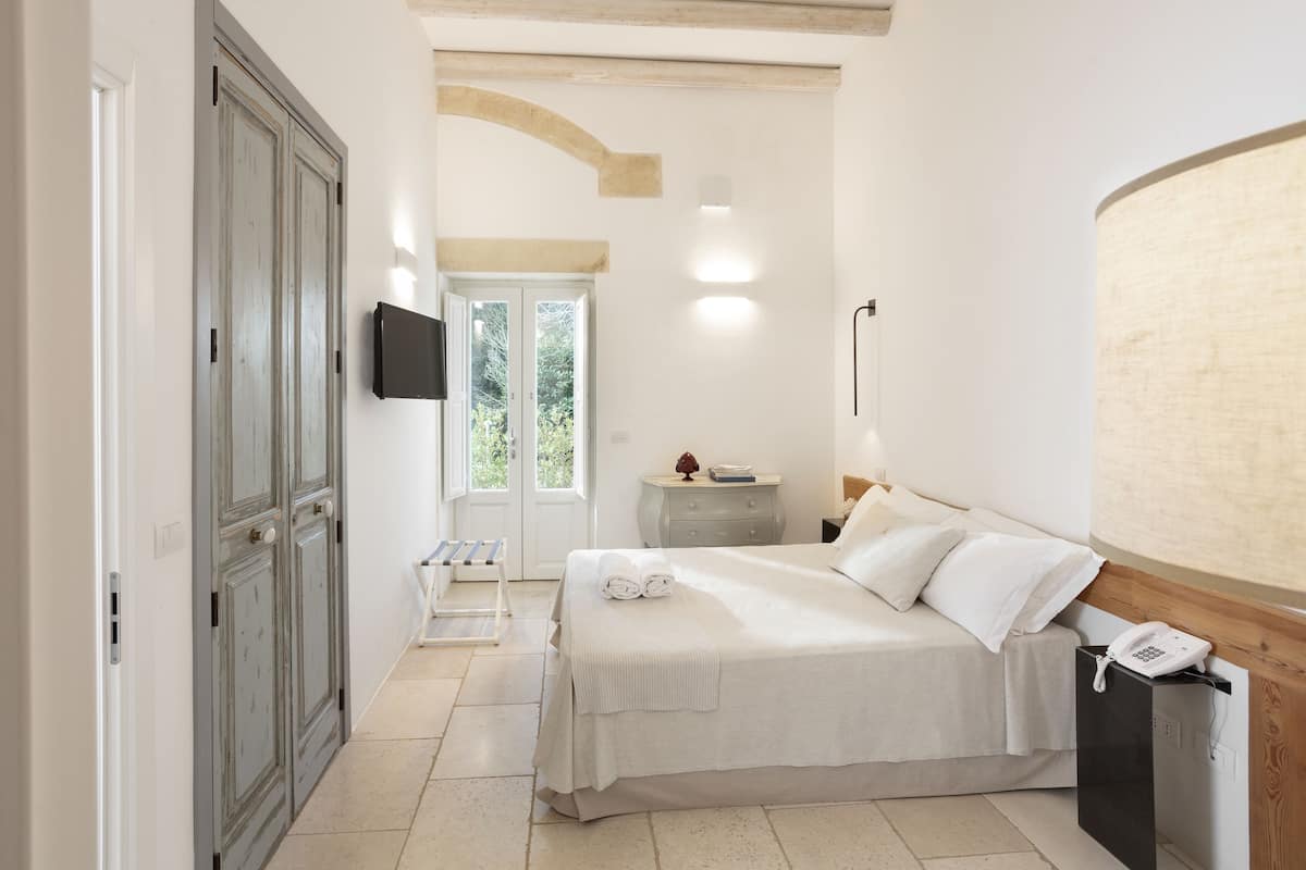 Une chambre à coucher comprenant un lit, une table de chevet, une lampe et un téléviseur fixé au mur.