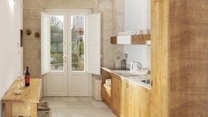 Una cocina con armarios de madera, encimera blanca y puerta que da a un jardín.