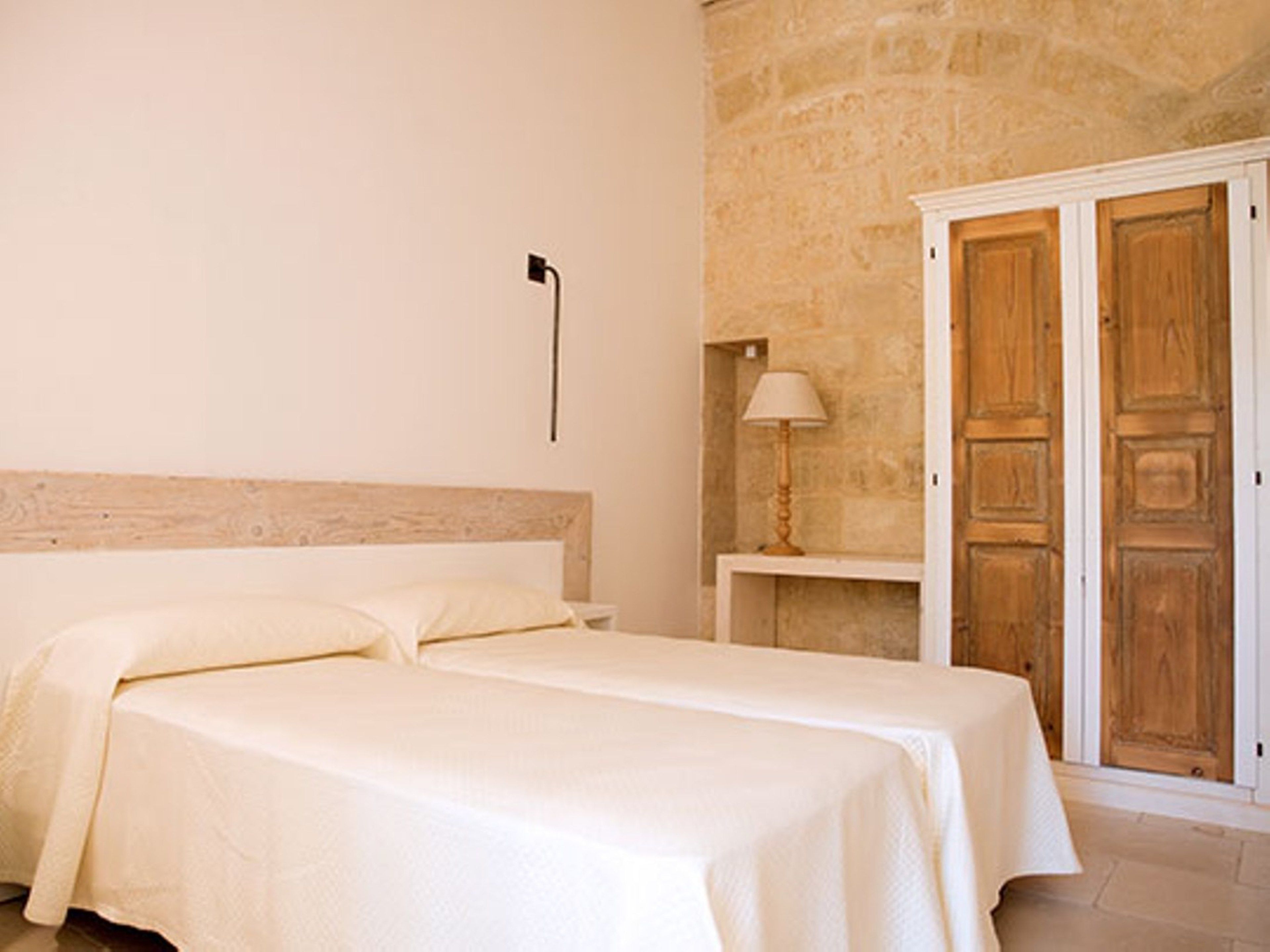 Un dormitorio con dos camas, una pared de piedra y un armario de madera.