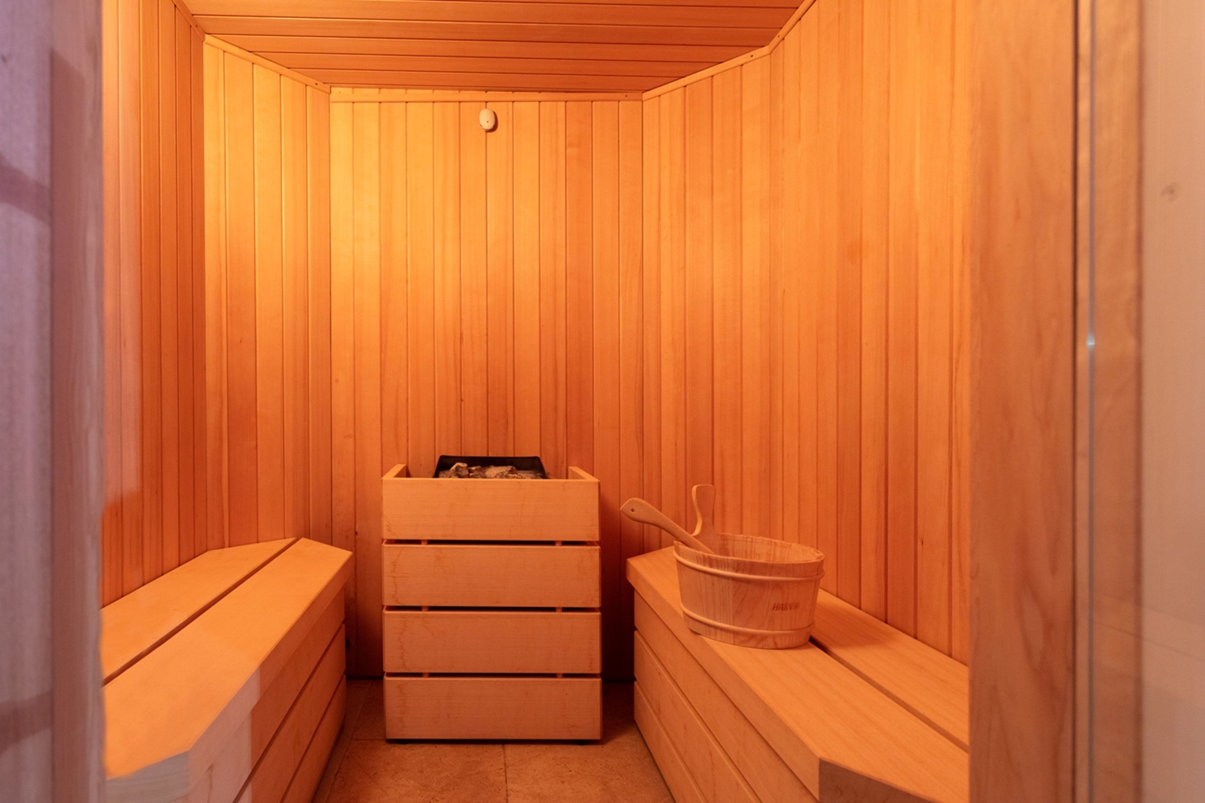 A wooden sauna with benches and a wooden bucket.