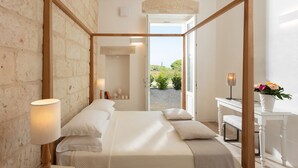 Un dormitorio con una cama con dosel de madera, un escritorio con silla y vistas al exterior.