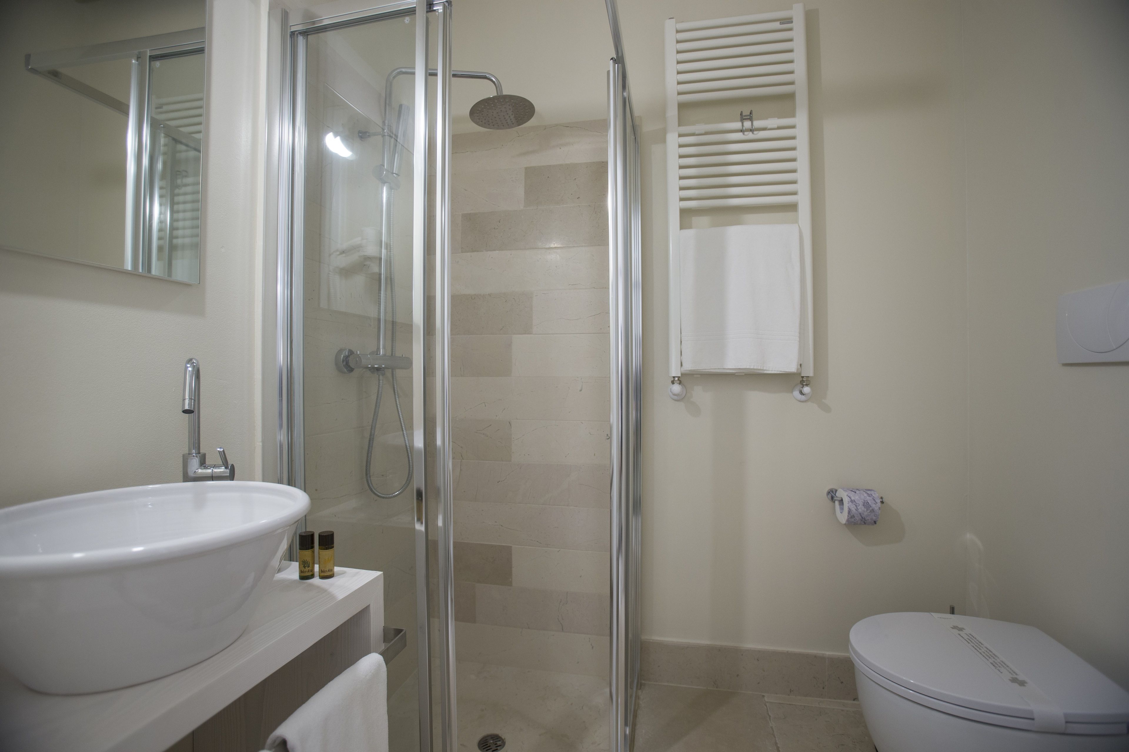 A bathroom with a glass-enclosed shower, a white sink, and a toilet.