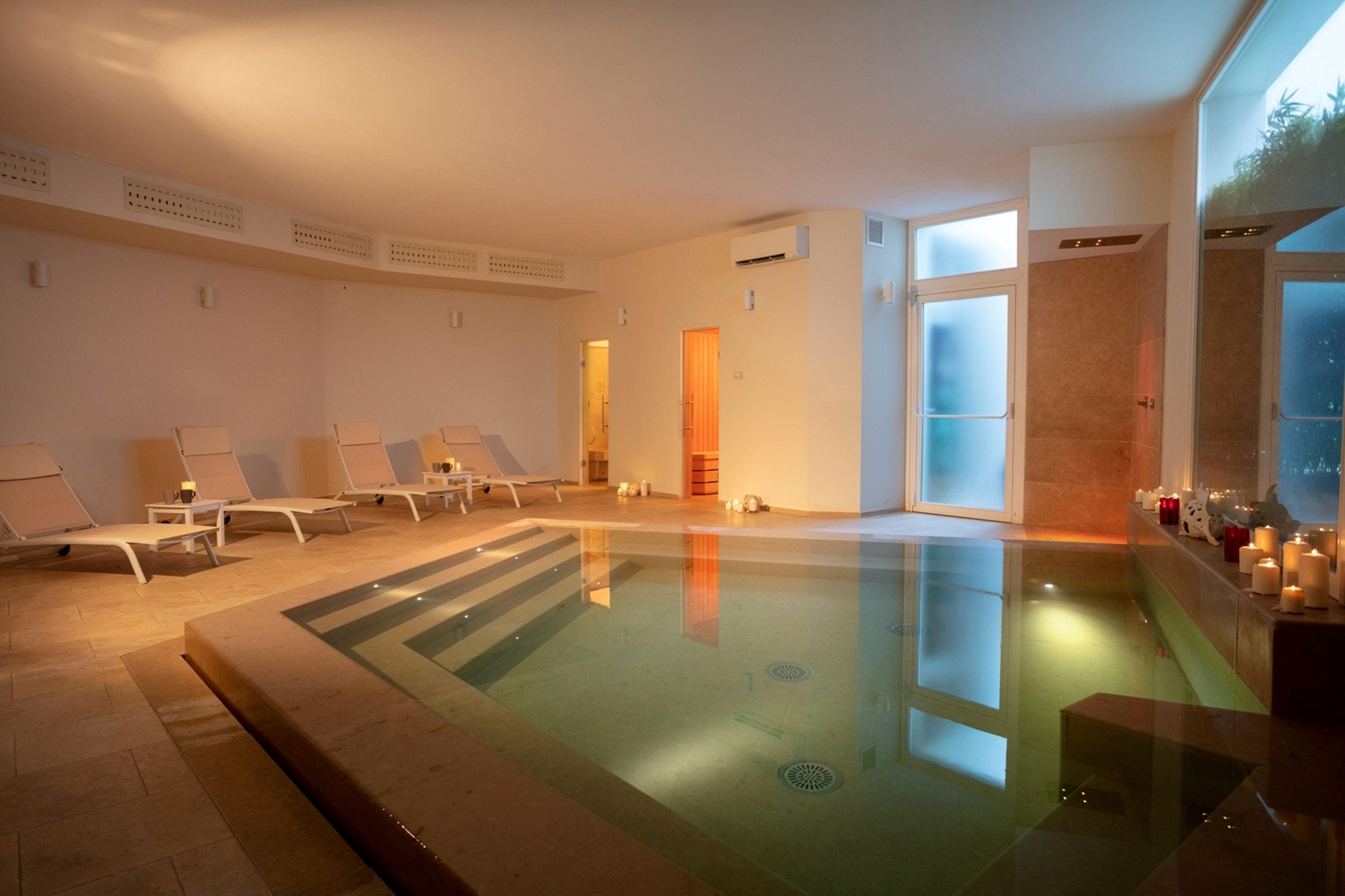 Ein Wellnessbereich mit Pool, Liegestühlen und Kerzen.