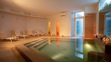 Ein Wellnessbereich mit Pool, Liegestühlen und Kerzen.