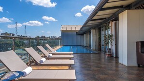 A rooftop terrace with lounge chairs, a swimming pool, and a view of the cityscape. - Swiss Lenana Mount Hotel (Nairobi)