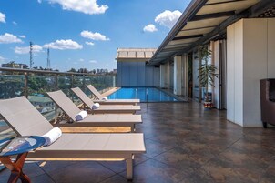 Una piscina al aire libre, sillones reclinables de piscina