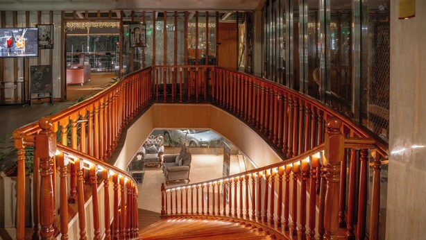A grand staircase with a wooden railing leading to a lower level. - Swiss Lenana Mount Hotel (Nairobi)