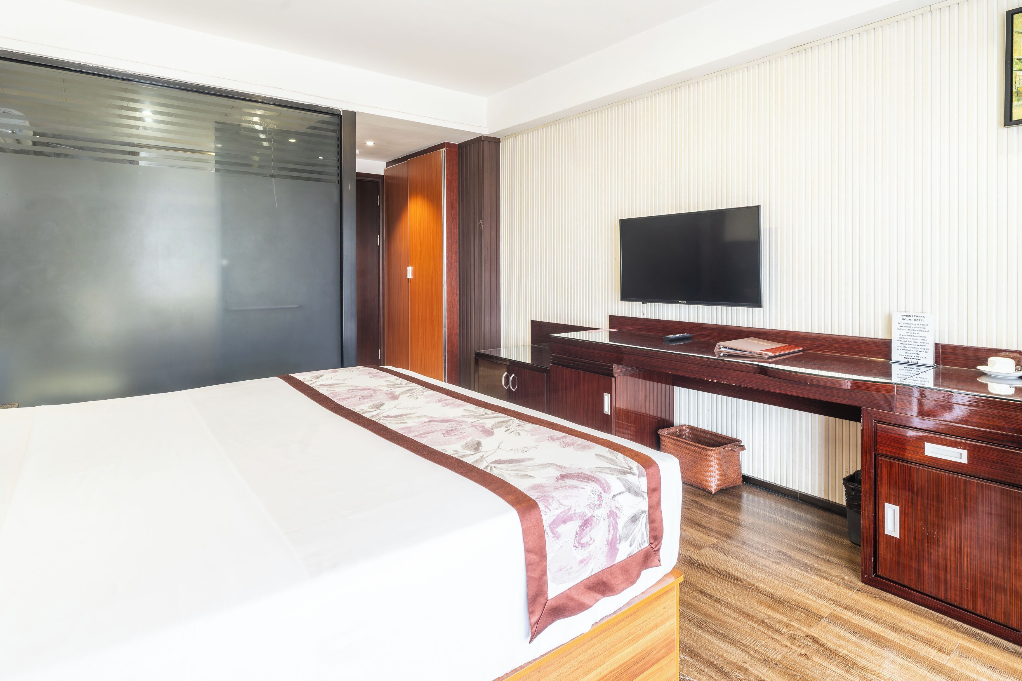 A hotel room with a bed, a desk, a television, and a wardrobe.