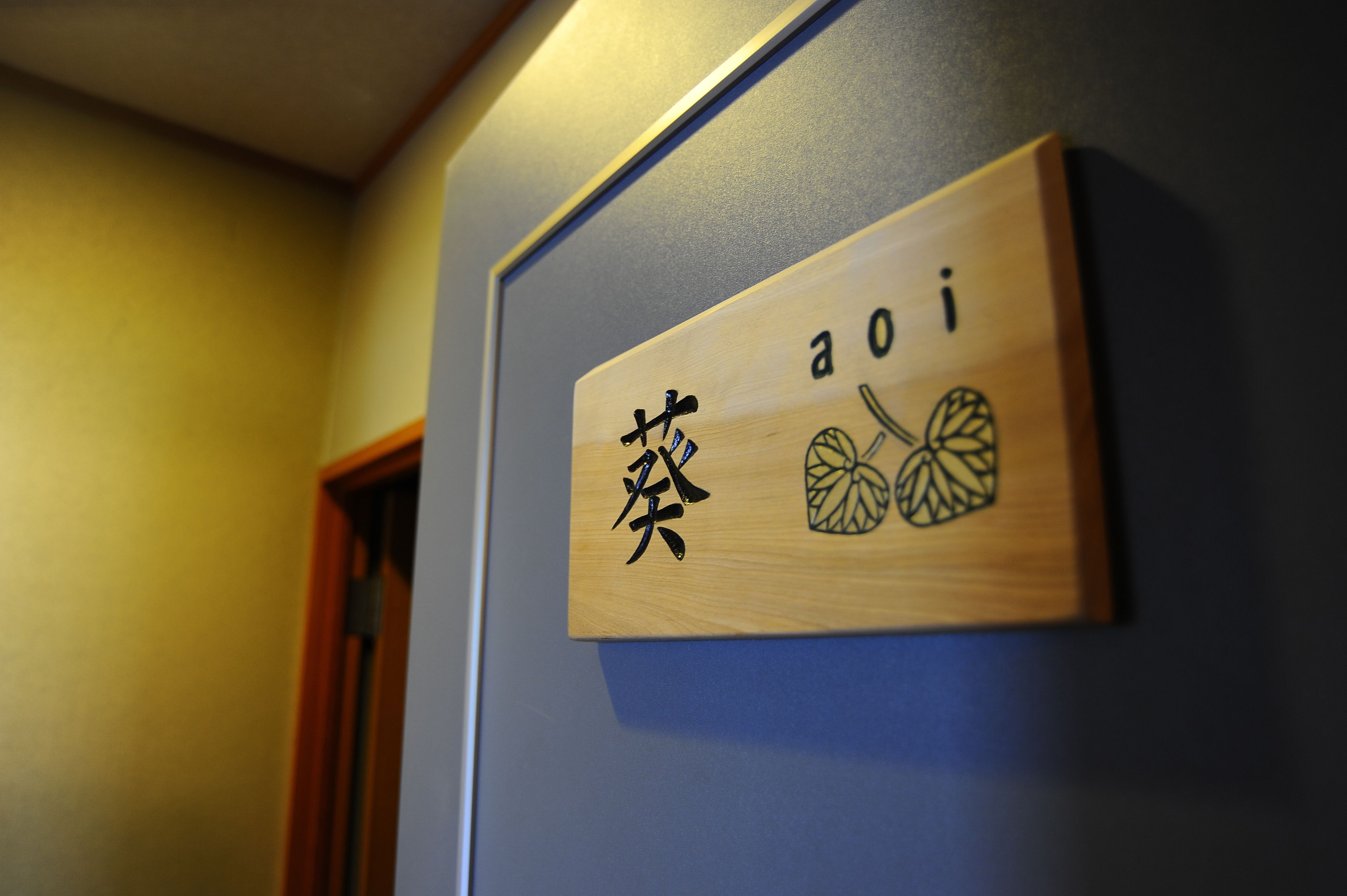 A wooden sign with Japanese characters and a fruit illustration on a wall.