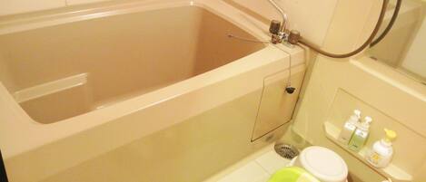 A bathroom with a bathtub, toilet, and a green child seat.