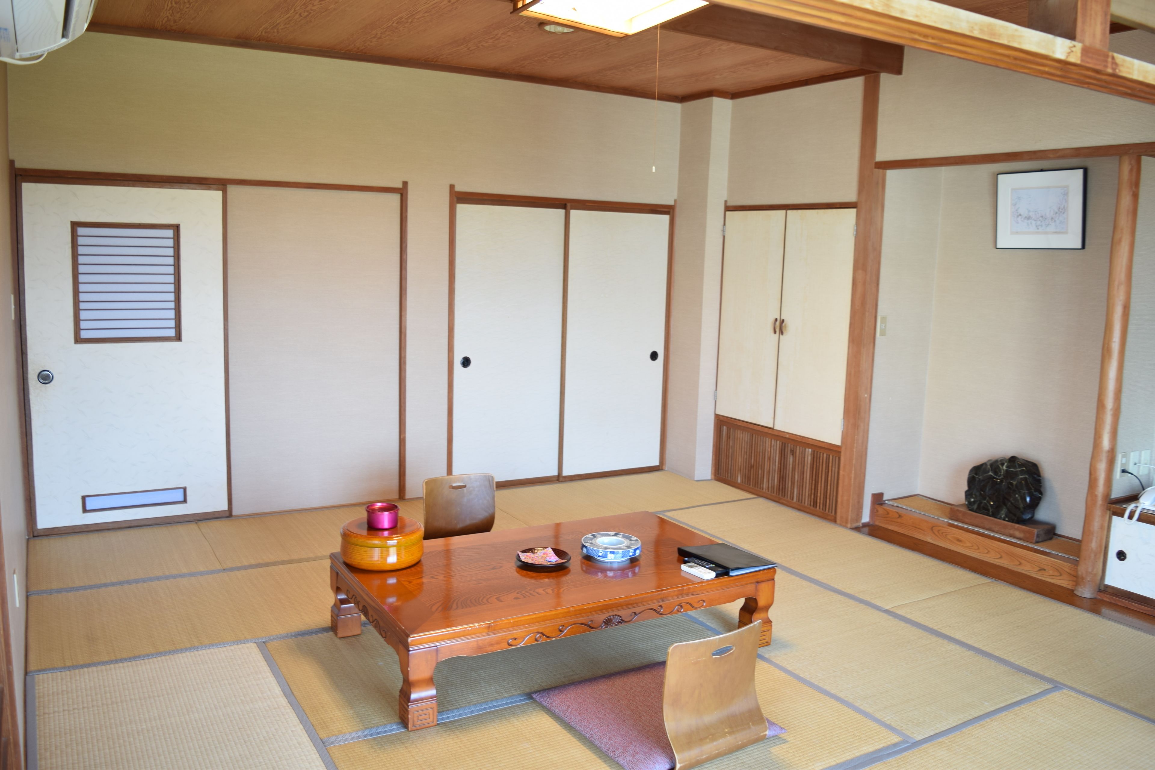 Ein traditioneller japanischer Raum mit Tatami-Bodenbelag, einem Holztisch und Schiebetüren.