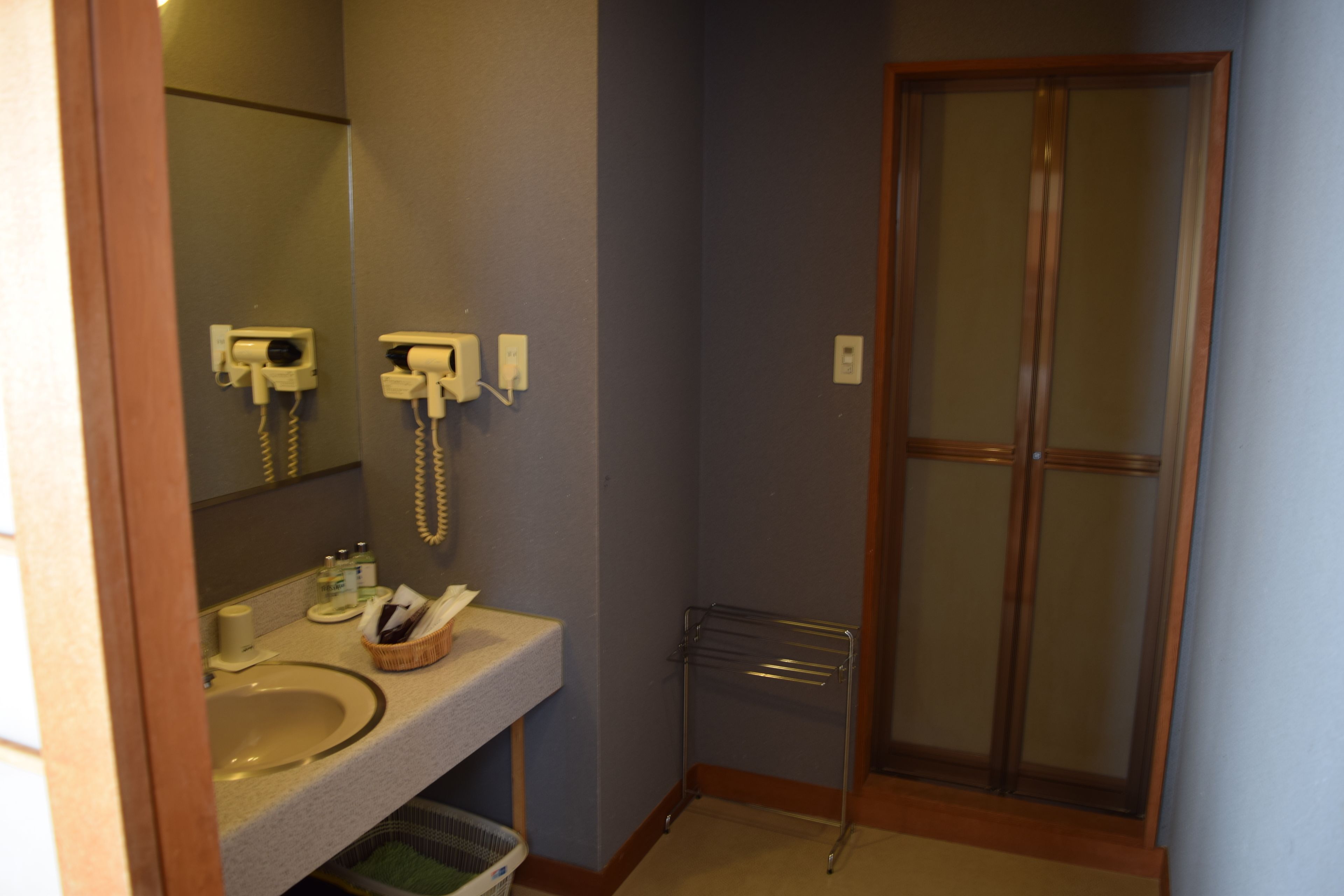 A bathroom with a sink, mirror, towel rack, and a shower door.