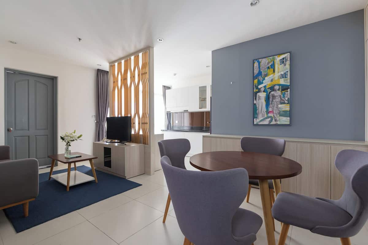 A modern living room with a dining area, a TV on a stand, and a painting on the wall.