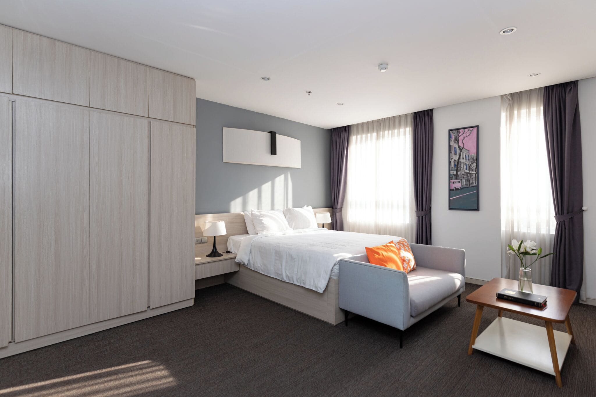 Une chambre d’hôtel moderne équipée d’un lit, d’un canapé, d’une table de chevet, d’une table et d’une armoire.
