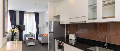 Eine moderne Küche mit Einbauofen, Kühlschrank und Toaster. Es gibt einen Essbereich mit einer Couch und einem Couchtisch.