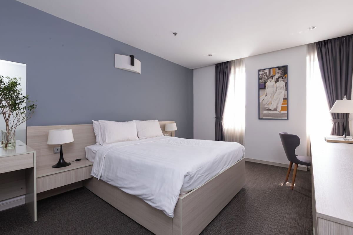 A modern hotel room with a large bed, bedside tables, a desk, and a chair.