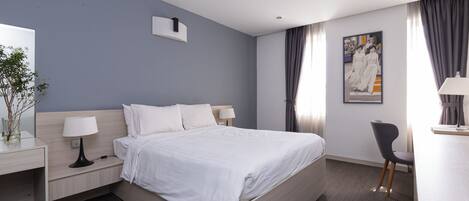 A modern hotel room with a large bed, bedside tables, a desk, and a chair.