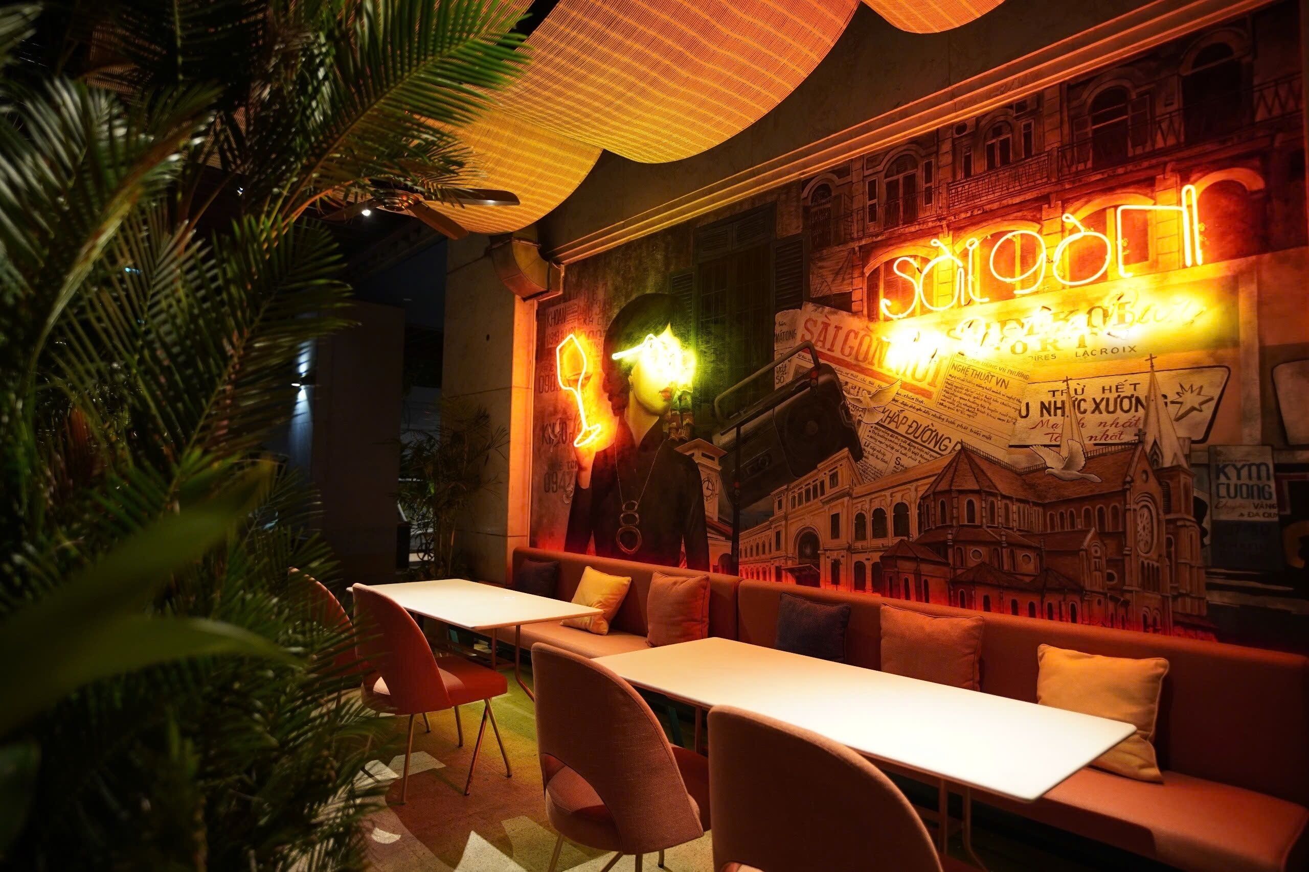 Un restaurant avec une enseigne au néon, une fresque murale et un espace où sont disposées des tables et des chaises.