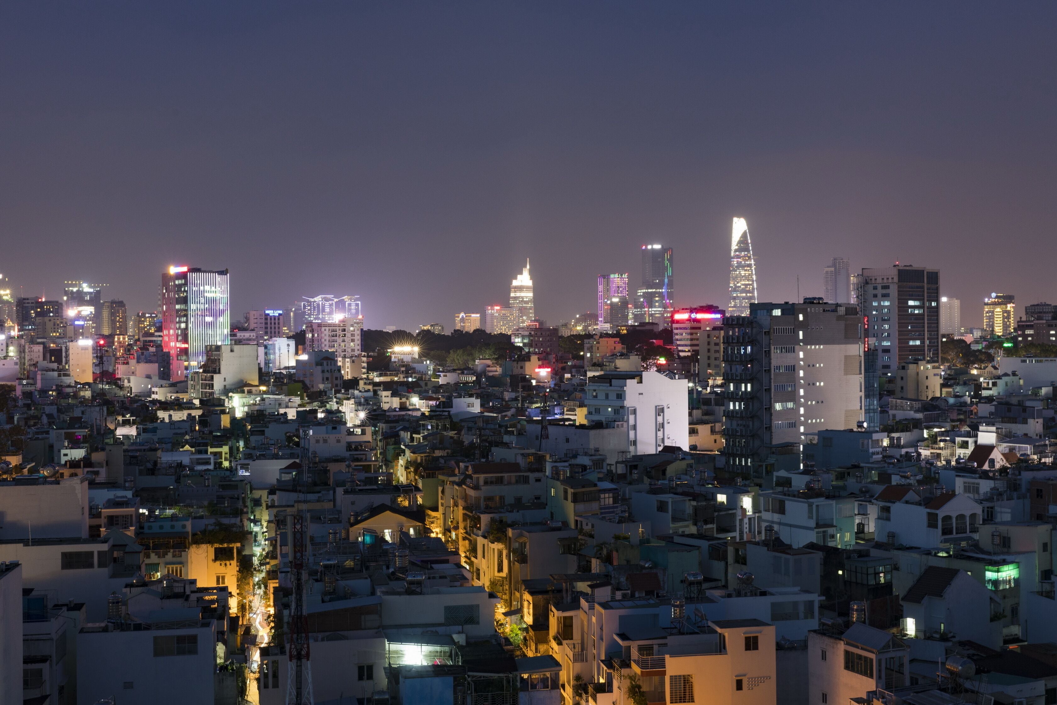 A densely packed urban skyline at night with illuminated buildings and a river running through the city.