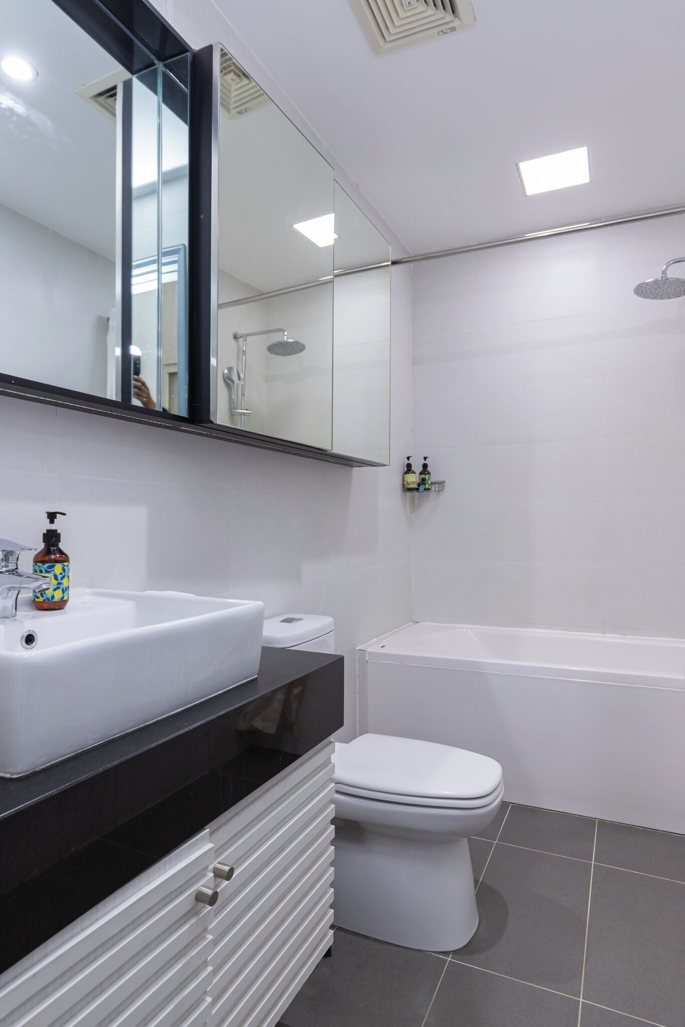 A modern bathroom with a white sink, black countertop, white toilet, and a bathtub.