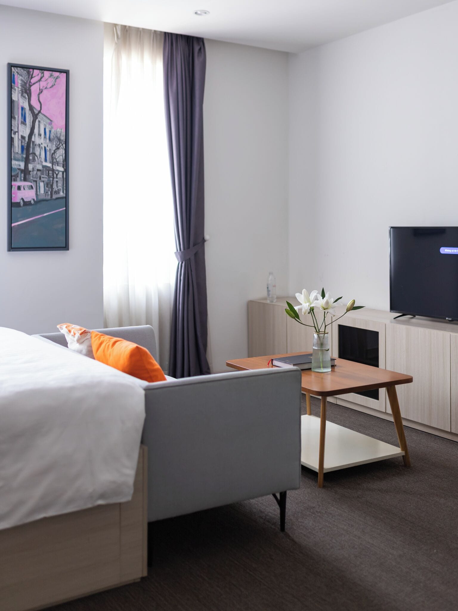 Una habitación de hotel moderna con cama, sofá, escritorio y televisor.