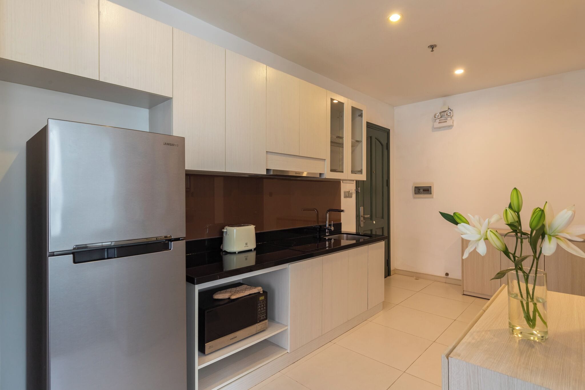 A modern kitchen with stainless steel appliances, white cabinetry, and a black countertop.
