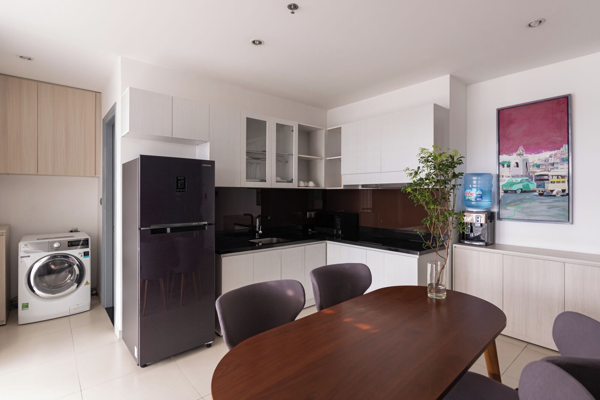 A modern kitchen with white cabinets, a built-in dishwasher, and a large water dispenser.
