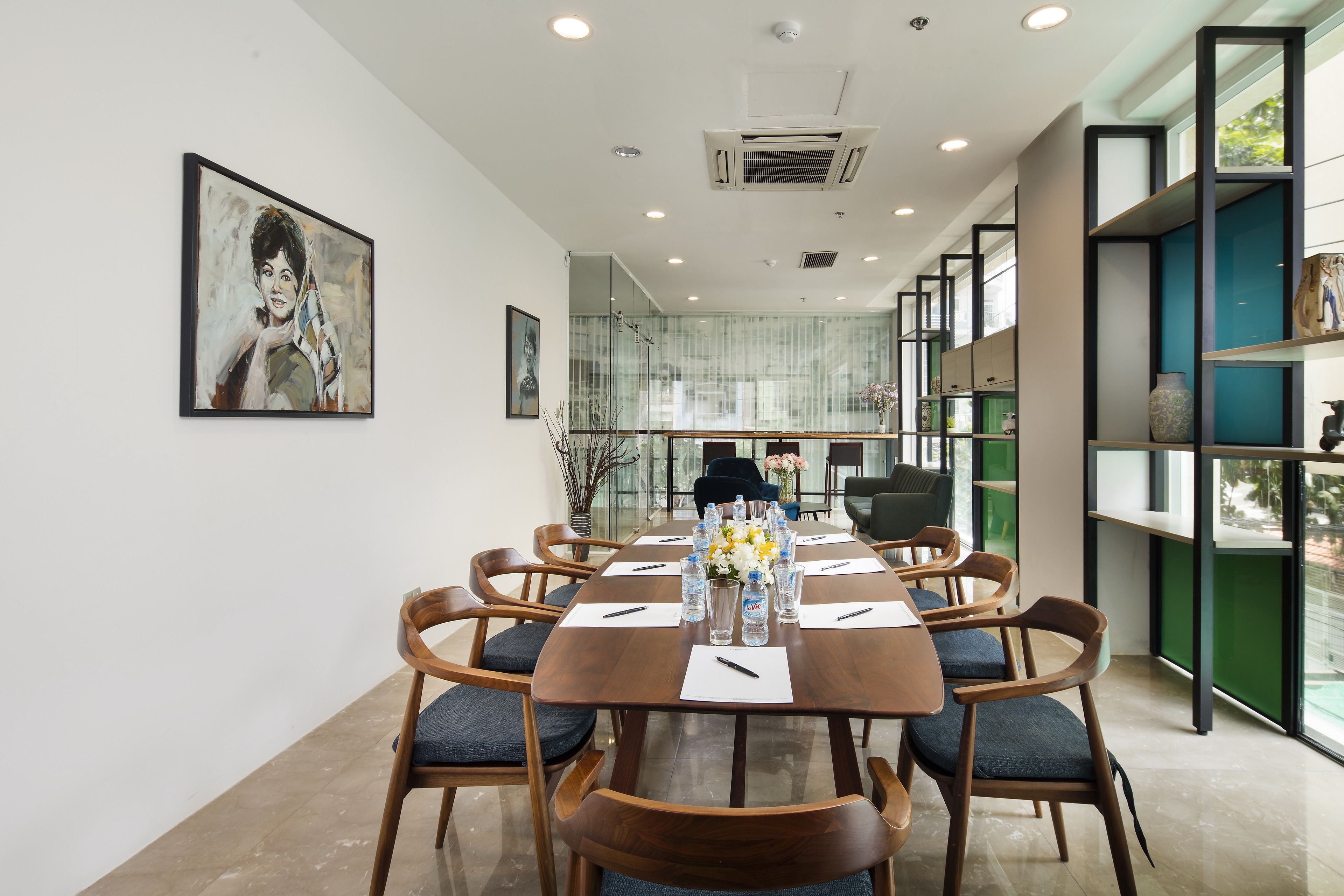 A conference room with a long table, chairs, and a glass partition.