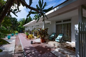 Un espace extérieur abrité, doté d’une terrasse, de plantes en pot et d’un coin salon avec des chaises.