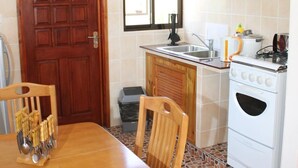 Une cuisine de taille réduite avec une table à manger en bois, des chaises, une cuisinière et un évier.