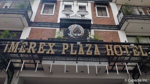 Das äußere Erscheinungsbild des Imrex Plaza Hotels mit einer auffälligen Beschilderung, schmiedeeisernen Verzierungen und einer Ziegel-Fassade.