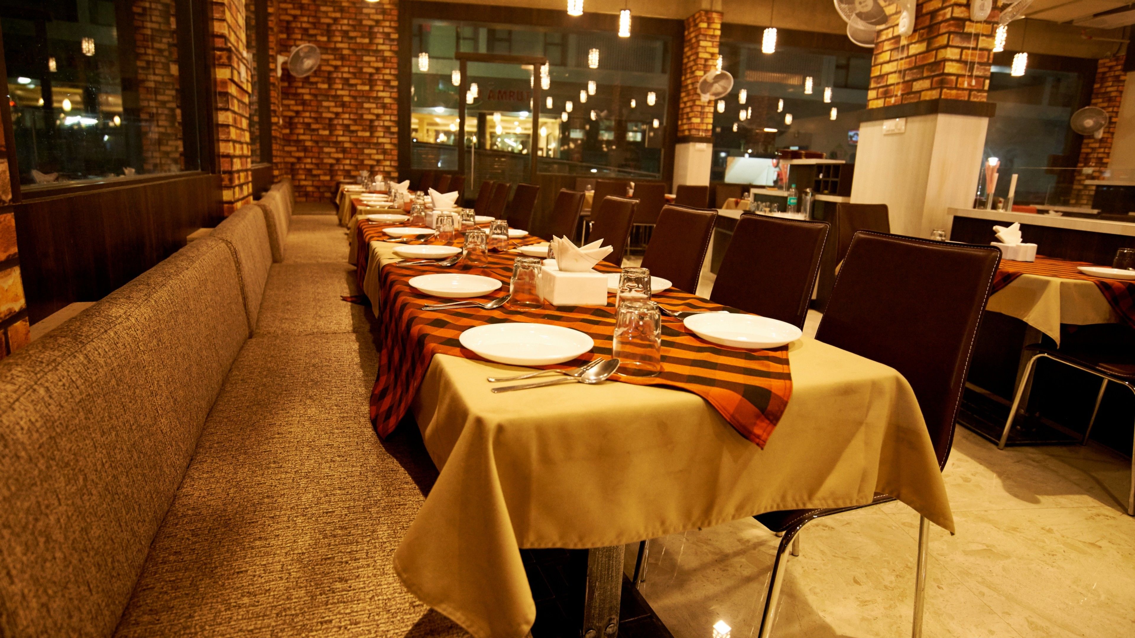 A restaurant with long tables, chairs, and a brick wall.