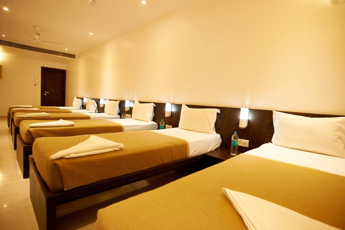 Habitación de hotel con varias camas, cada una con cabecera y mesitas de noche.